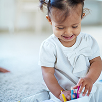 Young smiling child playing with colorful pencils.